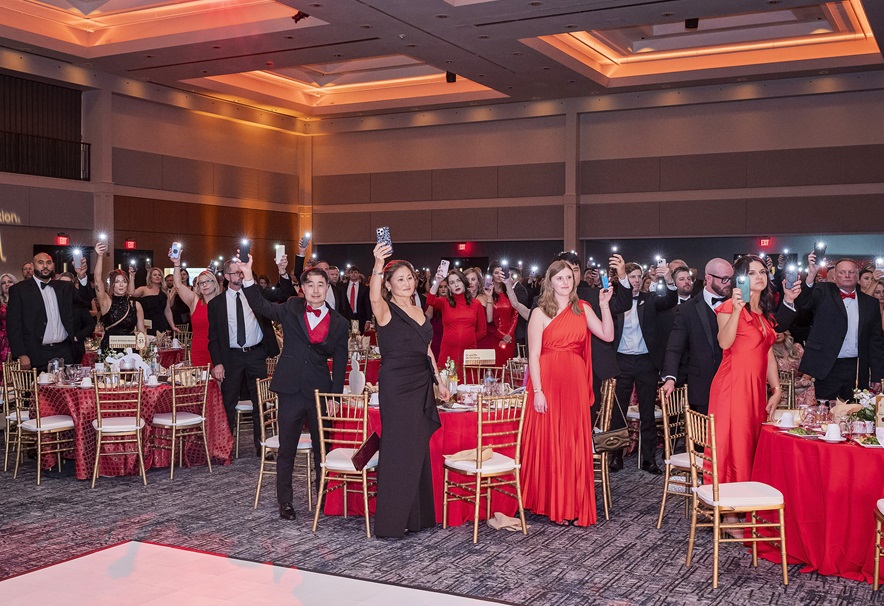 Photo of ball room full of people holding up phones in flashlight mode.